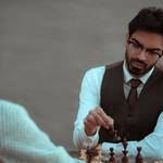 serious ethnic man making move with chess figure
