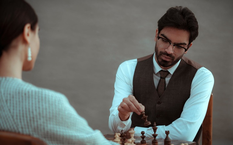 serious ethnic man making move with chess figure