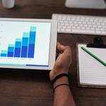 person holding white ipad on brown wooden table