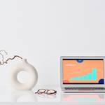 laptop beside a ceramic vase